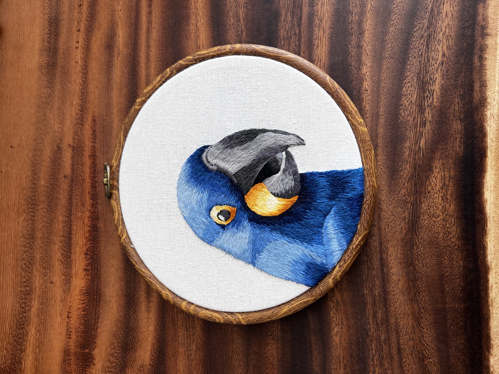 A hyacinth macaw hand-embroidered in cobalt-blue thread with a gold and grey beak.