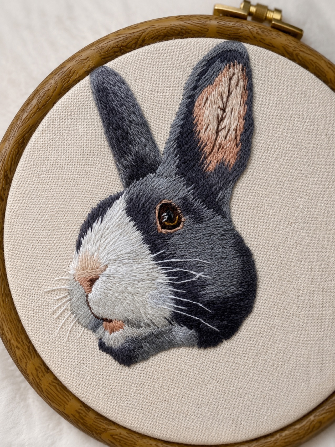 A grey-and-white rabbit hand-embroidered in soft fur-direction stitches.